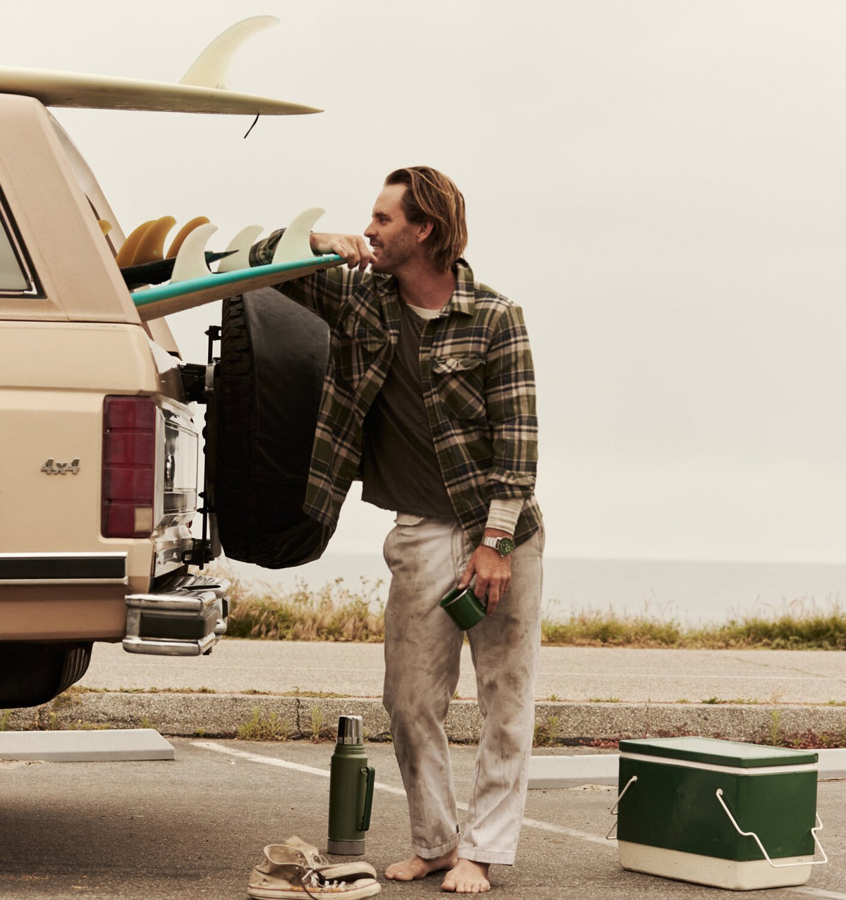 Man leaning on a surfboard in the back of his truck wearing a flannel and the Cali Diver Solar bracelet watch.