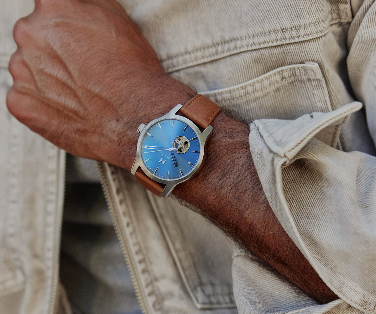 Man in denim jacket wearing a men's Classic II Automatic watch with blue dial and brown strap