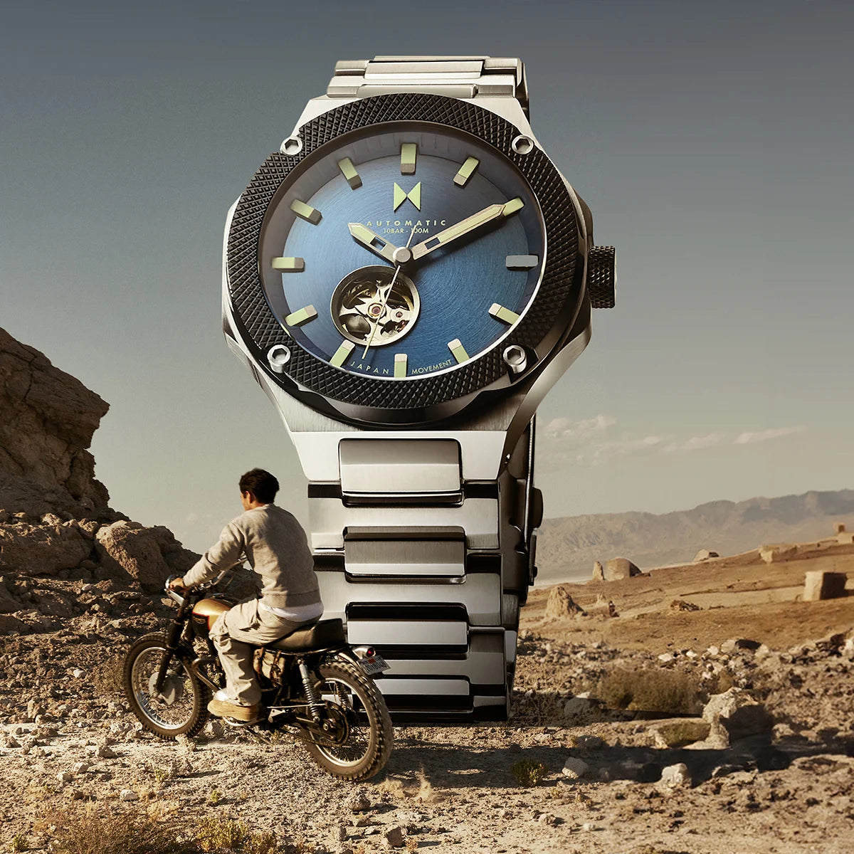 Men's Raptor Automatic watch on stone next to man on motorcycle